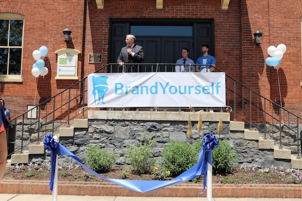 Mayor Rick Gray addresses the crowd while BrandYourself co-founders Patrick Ambron and Pete Kistler look on.
